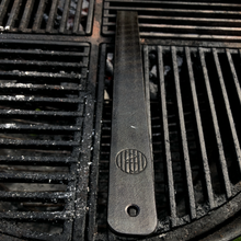 Load image into Gallery viewer, Close up of Axel Perkins Brand on universal grill handle gripping a weber grill. 
