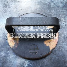 Load image into Gallery viewer, Axel Perkins Heirloom Burger Press on a flat steel plancha with label text overlay
