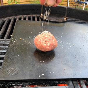 Burger on the Axel Perkins Plancha being seasoned before being smashed