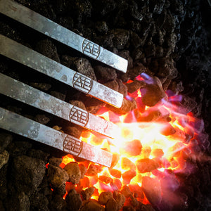 Hand forging skewers on a bed of coals